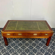 Load image into Gallery viewer, Introducing a unique piece of craftsmanship - a mahogany coffee table in the military campaign style. This stunning table, made in England around the 1950s, features a design that will pique your interest with its formal and executive look.
