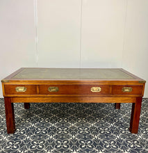 Load image into Gallery viewer, Introducing a unique piece of craftsmanship - a mahogany coffee table in the military campaign style. This stunning table, made in England around the 1950s, features a design that will pique your interest with its formal and executive look.
