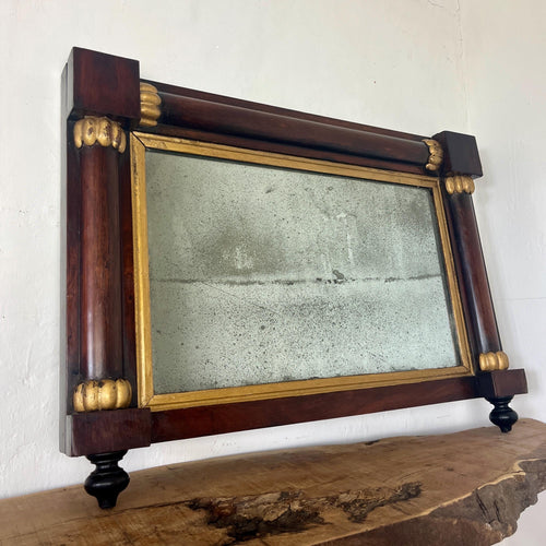 A mid-19th-century rosewood overmantle mirror in landscape form, the frame has classical columns to the sides, and top with gilt collars, and the gilt frame edging has detailed ball feet to create a standout period design.