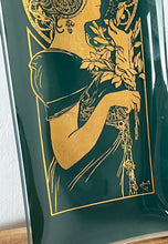Load image into Gallery viewer, Vintage large glass tray in the deep green background with Alphonse mucha the feather picture in gold. Mucha portrays a young woman surrounded by lush foliage and delicate feathers. The figure is depicted in profile, and she wears a flowing gown.
