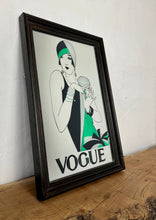 Load image into Gallery viewer, The photo features a woman wearing a stunning art deco dress and hat with block colors of black, green, and grey. She has a chic short bob haircut and is accessorized with stacked bracelets on both arms. The Vogue logo is displayed at the bottom.

