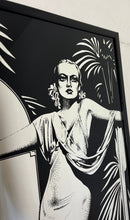 Load image into Gallery viewer, Carole Lombard, in her glamorous gown designed by Irene in the film To Be or Not to Be. The intricate design of her dress and the surrounding palm trees create a beautiful composition that is enhanced by the noir effect finish.
