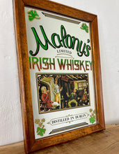 Load image into Gallery viewer, The mirror is beautifully designed with vibrant fonts in a multi-coloured tone, reminiscent of the Irish flag. The image captures the essence of the old days with a fireside scene and a pretty border designed with three-leaf clovers.
