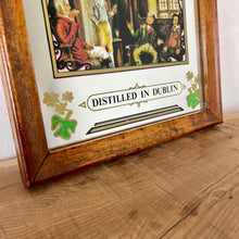 Load image into Gallery viewer, The mirror is beautifully designed with vibrant fonts in a multi-coloured tone, reminiscent of the Irish flag. The image captures the essence of the old days with a fireside scene and a pretty border designed with three-leaf clovers.
