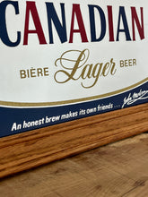 Load image into Gallery viewer, Striking red and blue designs, a gold maple leaf, and a detailed gold border, all complemented by a sleek pine frame. The Molson slogan is at the bottom.
