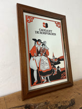 Load image into Gallery viewer, The mirror depicts a traditionally dressed French couple with the village in the background. The background includes trees, hills, and a lake. comes in vibrant orange, black, and white colours with a gold finish.
