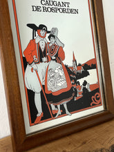 Load image into Gallery viewer, The mirror depicts a traditionally dressed French couple with the village in the background. The background includes trees, hills, and a lake. comes in vibrant orange, black, and white colours with a gold finish.
