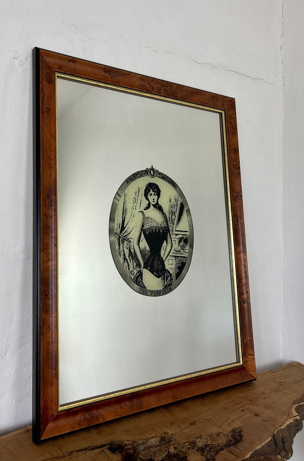 The mirror depicts a glamorous Victorian lady in an oval design with a noir effect, and it includes intricate details and a provocative finish. The walnut frame is of high quality and dates back to the 1920s.