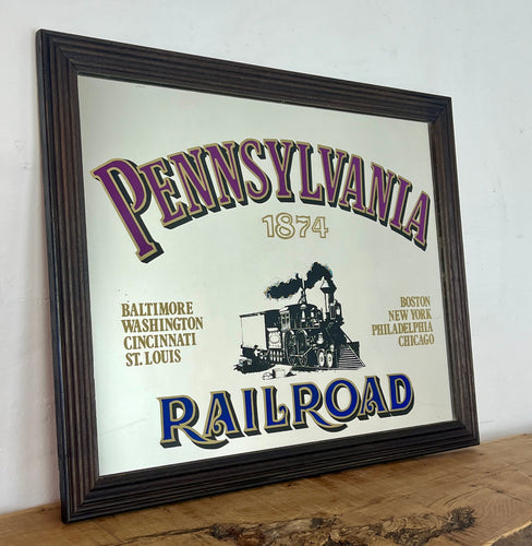 Historical Pennsylvania Railroad Company 1874 advertising mirror, showing the detailed steam train in a intricate noir design, bold stand out font with multiple vivid tones, with a list of the cities where the station are located.