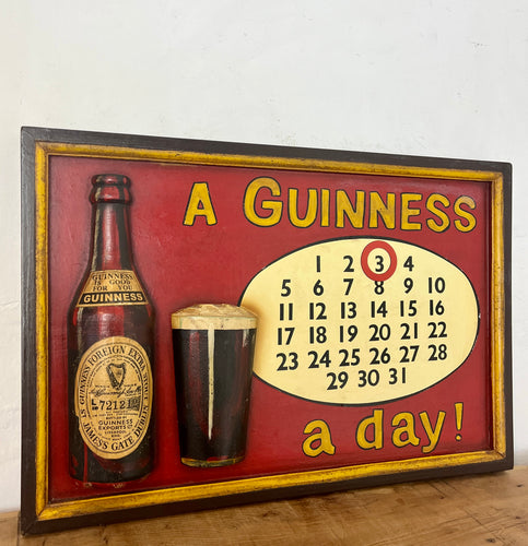 Stunning Guinness vintage calendar plaque showing detailed model of the foreign extra bottle and glass with marvellous matt tones with an aged label, the piece design in a intricate detailed finish, hand painted fonts.